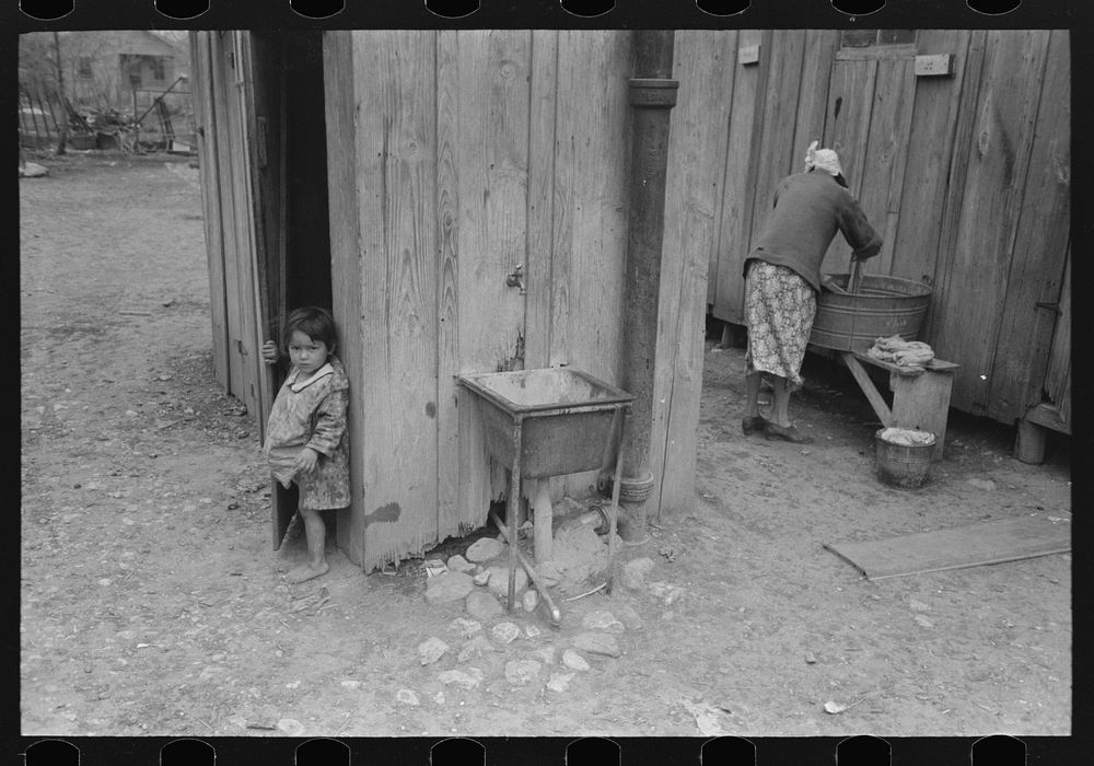 Mexican girl coming from privy, woman washing clothes, San Antonio, Texas by Russell Lee