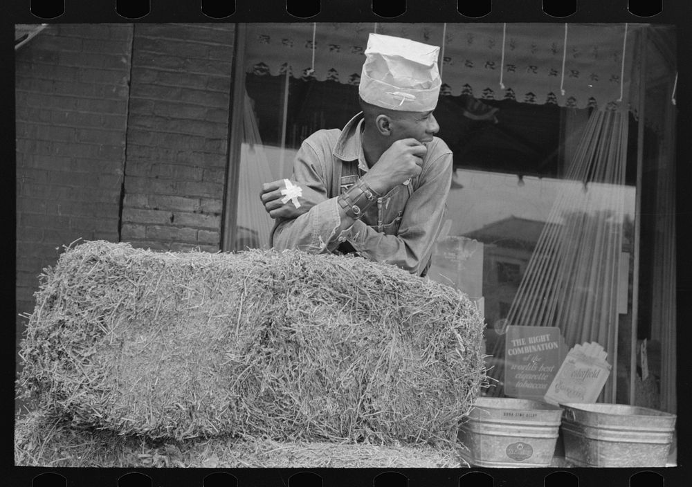  leaning on bale of hay, San Augustine, Texas by Russell Lee