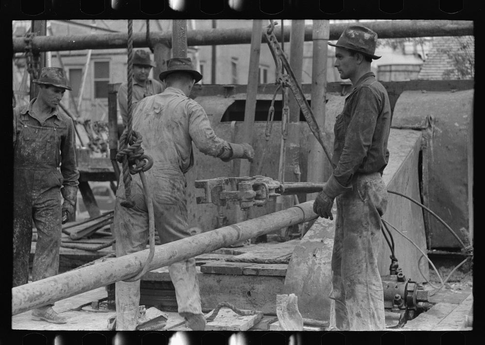 [Untitled photo, possibly related to: Oil field workers releasing pipe wrenches from drill pipe, oil well, Kilgore, Texas]…