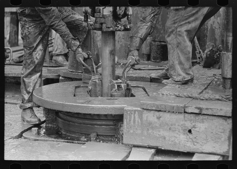 Removing clamps from rotary tacle before lifting out drilling pipe, oil well, Kilgore, Texas by Russell Lee