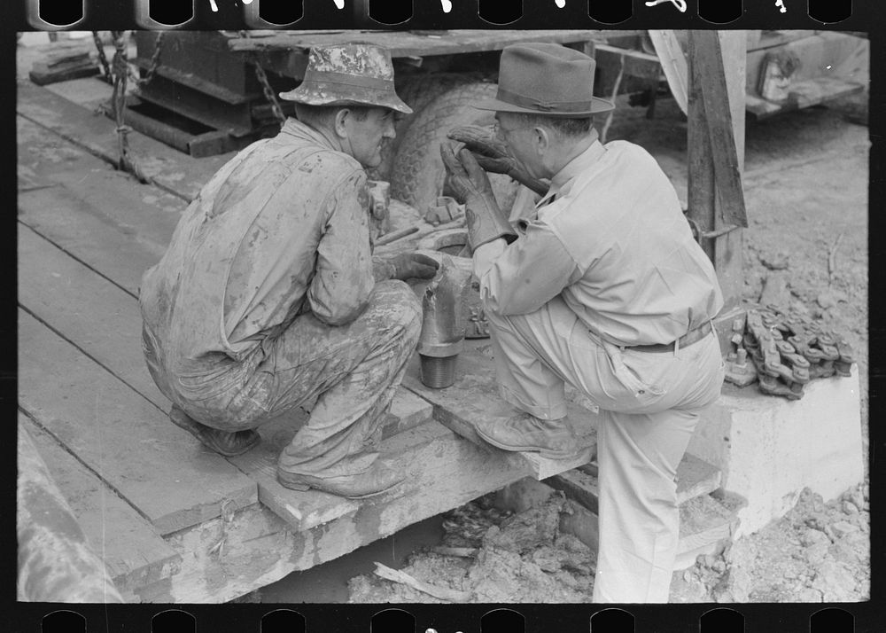 [Untitled photo, possibly related to: Oil field workers squatting down while talking to bit salesman, Kilgore, Texas] by…