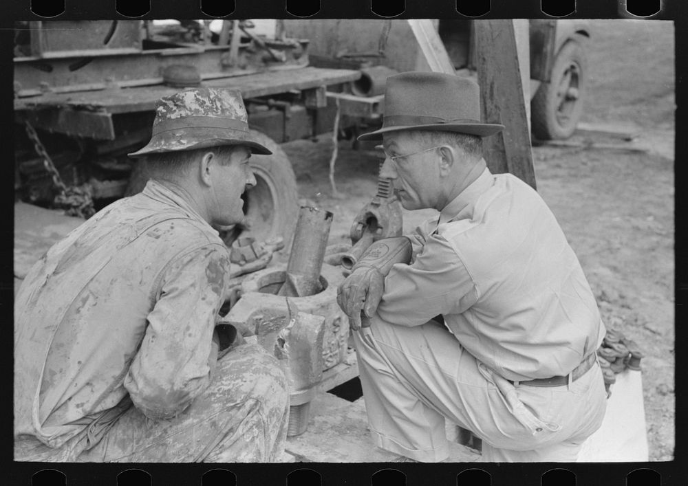 [Untitled photo, possibly related to: Oil field workers squatting down while talking to bit salesman, Kilgore, Texas] by…
