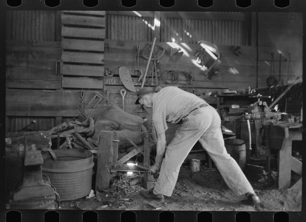 Blacksmith at work in his shop, San Augustine, Texas by Russell Lee