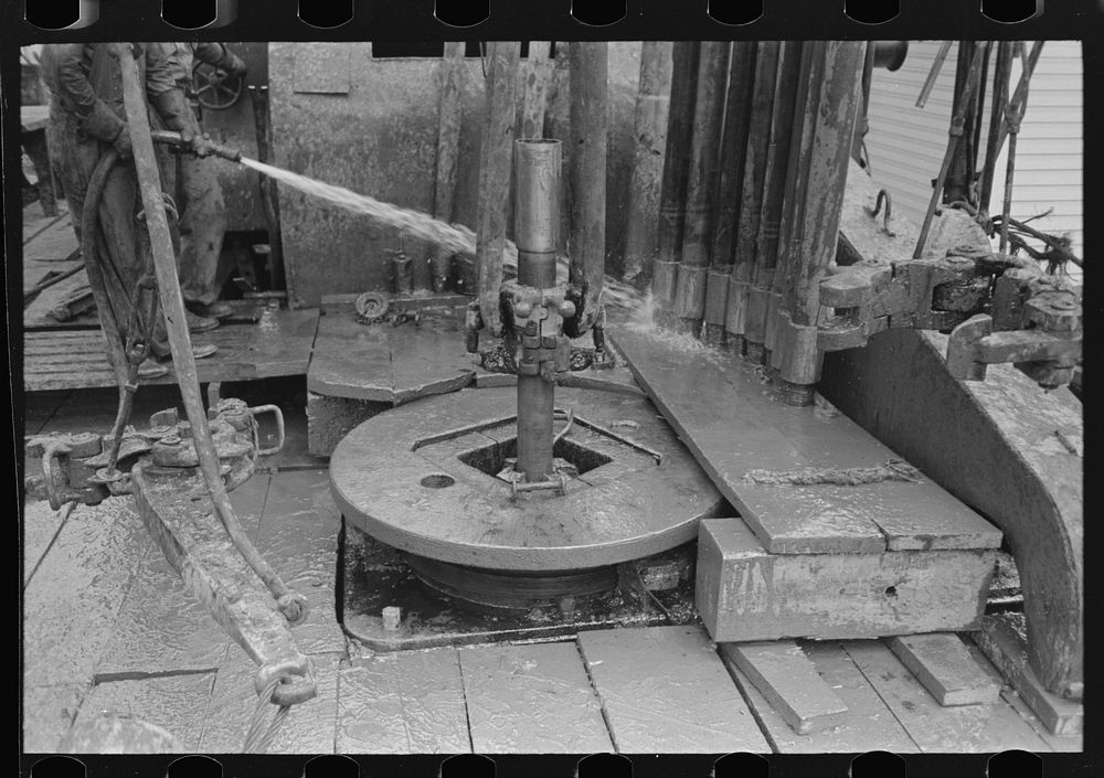 Rotary table, links and clamps of elevator with sections of pipe, oil well, Kilgore, Texas by Russell Lee