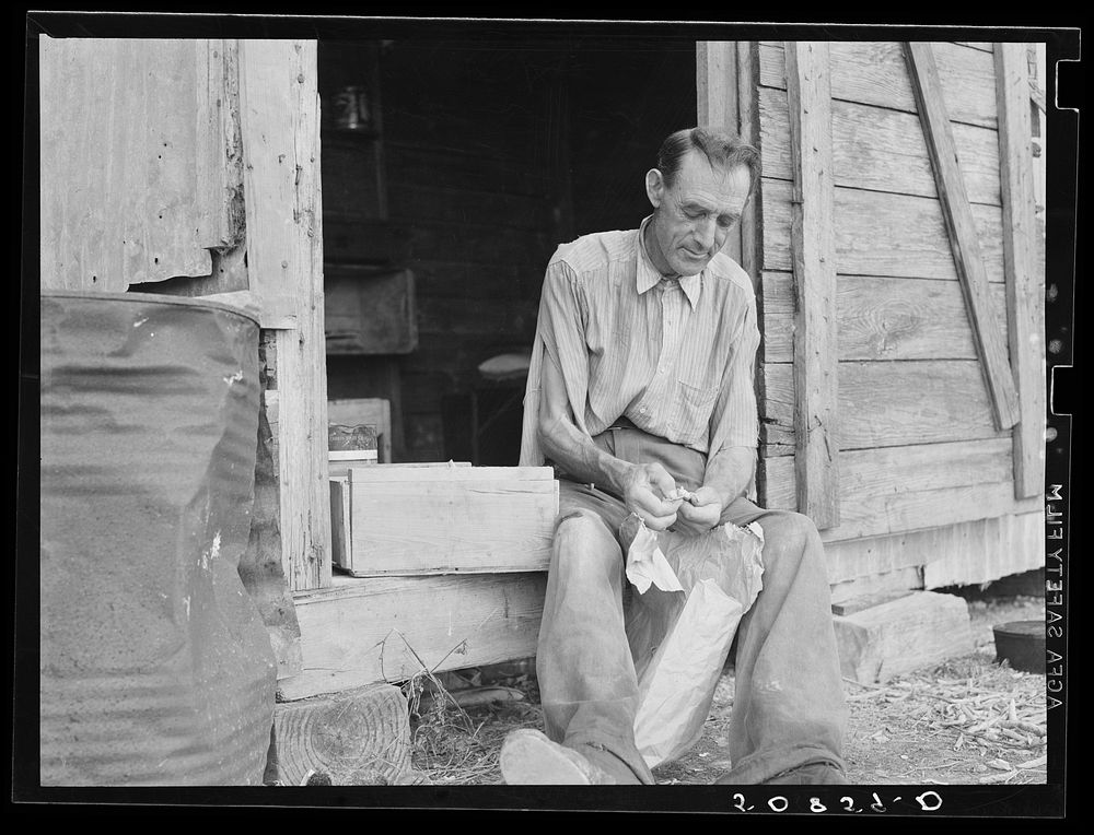 Former railroad worker shelling beans for his supper in front of his shack. He is now picking beans in Belle Glade, Florida.…
