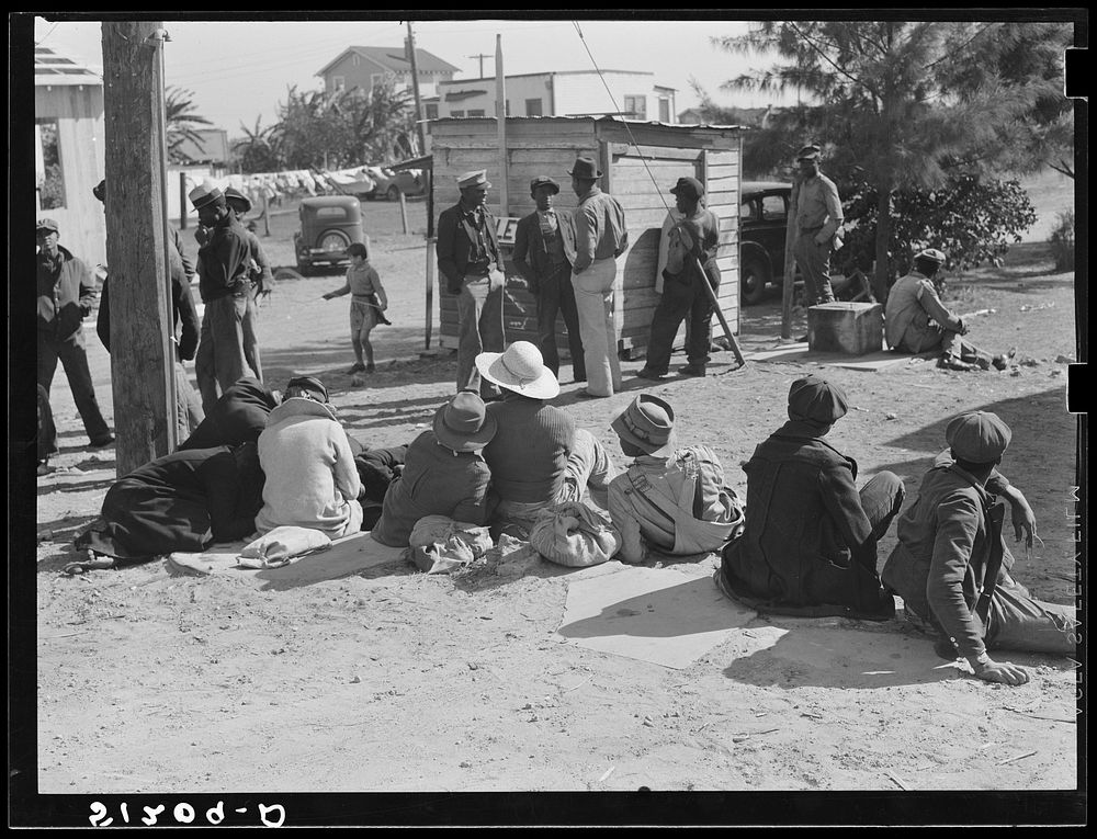 Migrant laborers waiting for truck to haul them to fields to pick beans. Near Lake Harbor, Florida. Sourced from the Library…