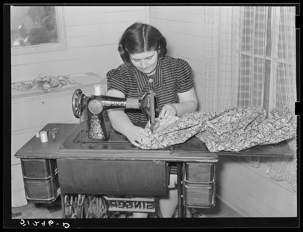 Mrs. Helms making dress. She does all her family sewing on new machine. FSA (Farm Security Administration) client. Coffee…