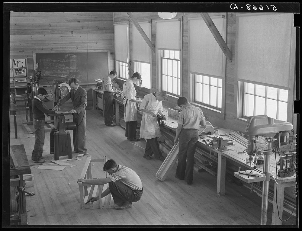 Part of shop class in school with Robert Gentry, teacher, in center at machine. Ashwood Plantations, South Carolina. Sourced…
