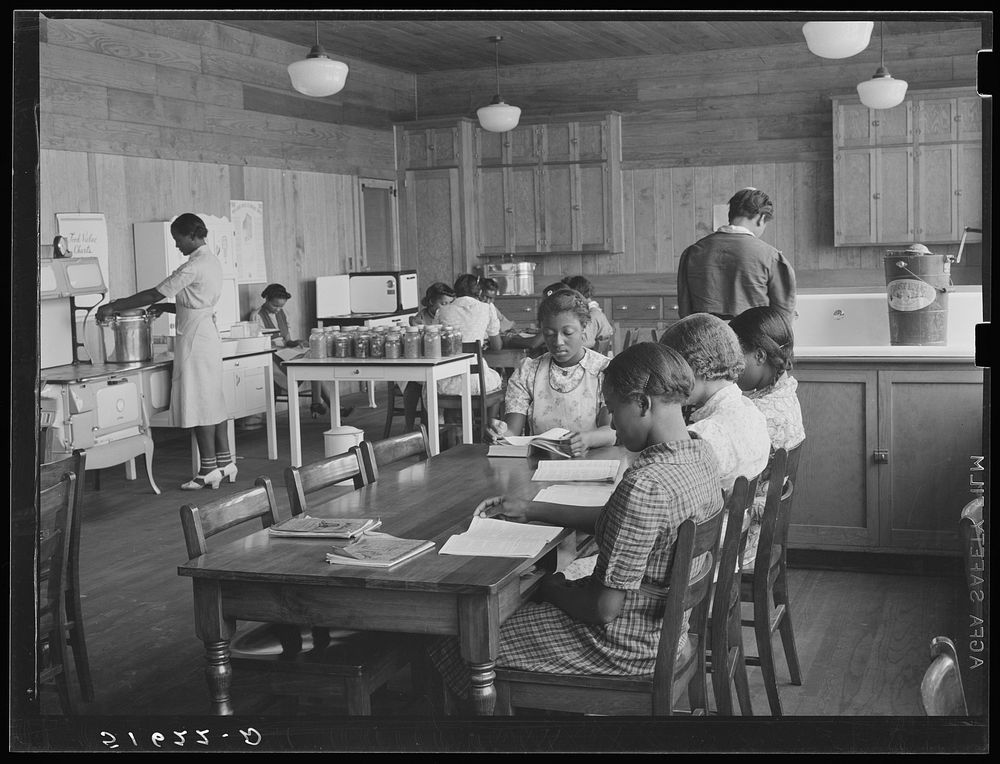 Members of eighth and eighth grades in home economics room, showing jars or vegetables and fruits they have canned with…