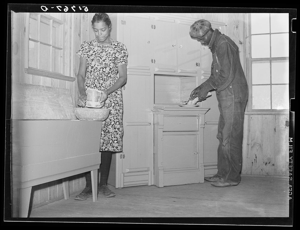 Project family in kitchen of their new home, showing cabinet and flour bin they built. Prairie Farms, Alabama. Sourced from…