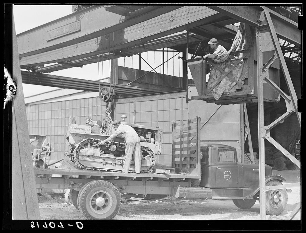 Hooking shepard crane to tractor preparatory to hoisting it off truck to repairs shop in FSA (Farm Security Administration)…