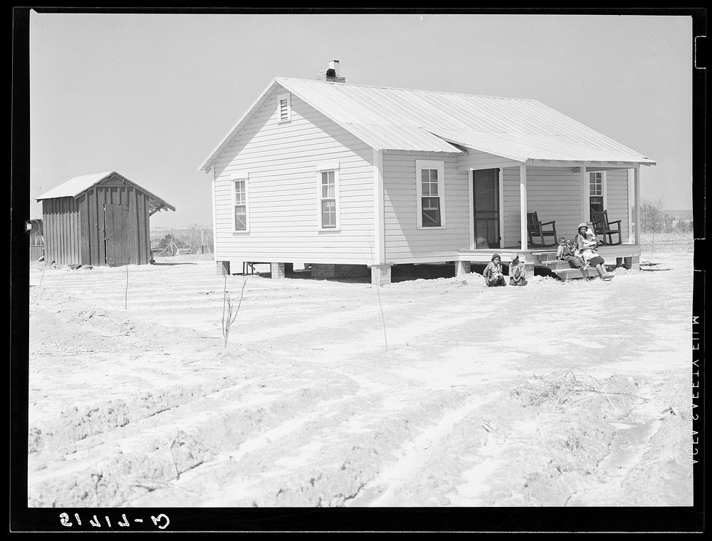 New home and smokehouse of Charles McGuire (tenant purchase borrower) with his wife and children on front porch. Pike…