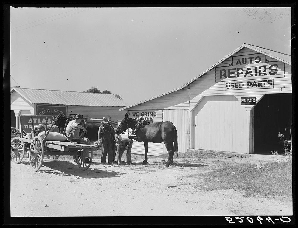 Combination filling station, garage, smith shop, grocery store. Frank Petty, owner of the wagon, has just had his mule shod…
