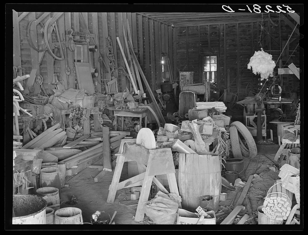 The smith and carpentry shop on Marcella Plantation, Mileston, Mississippi Delta. At the right is a piece of cotton hanging…