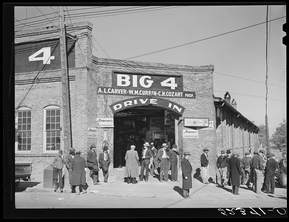 Farmers waiting around outside warehouse during tobacco auction sale. Durham, North Carolina. Sourced from the Library of…