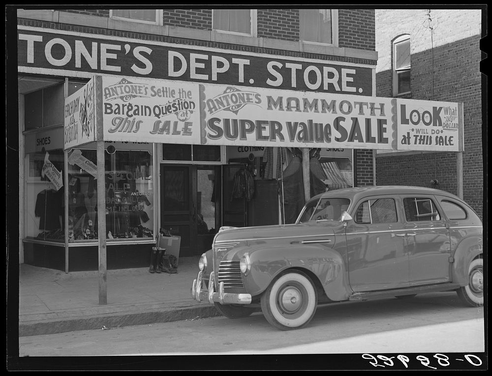 Signs on store windows advertising sales during tobacco auction time in Zebulon, Wake County, North Carolina. Sourced from…
