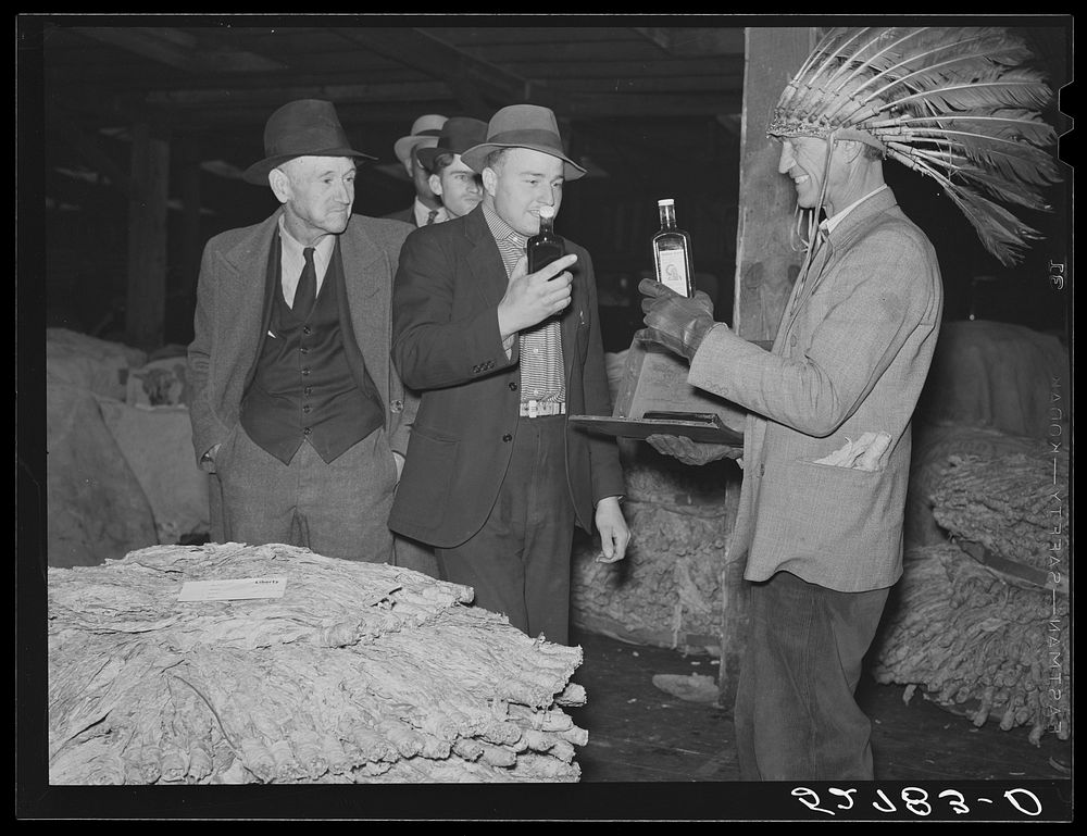 Farmers listening to sales talk of patent medicine vendor in warehouse during tobacco auctions. Durham, North Carolina.…