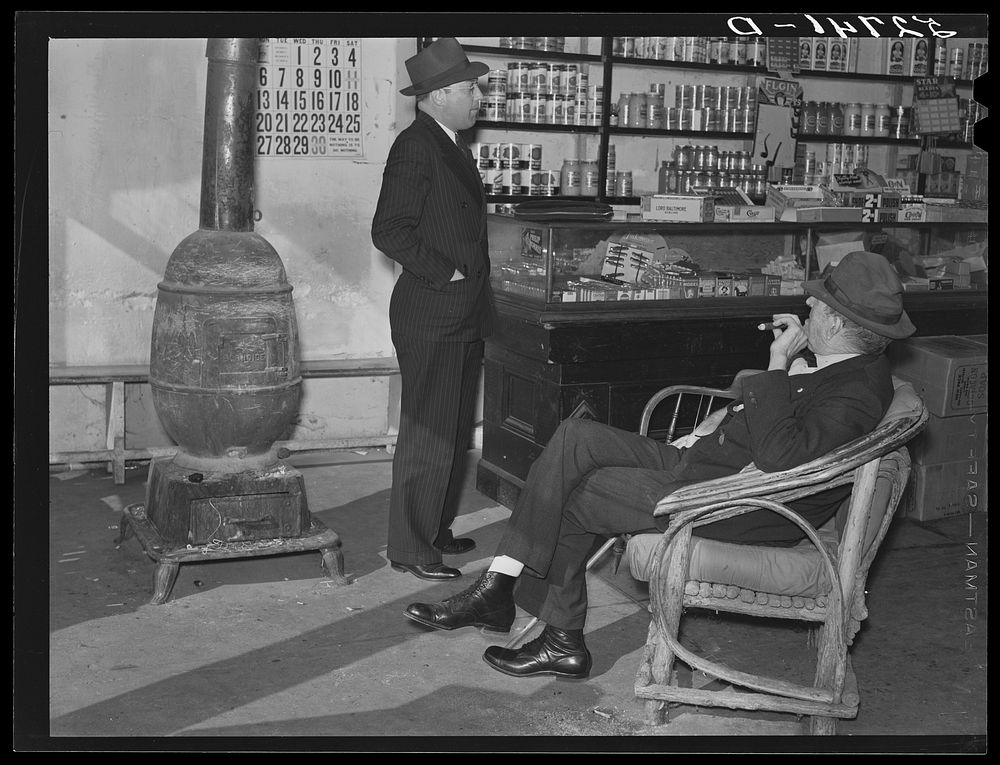 Mr. R.B. Whitley (in chair) visiting in his general store. He is president of the bank and practically owns and runs the…