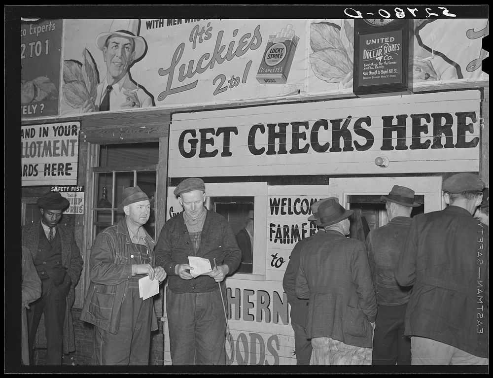 Farmers getting their checks in warehouse office after their tobacco has been sold at auction. Durham, North Carolina.…