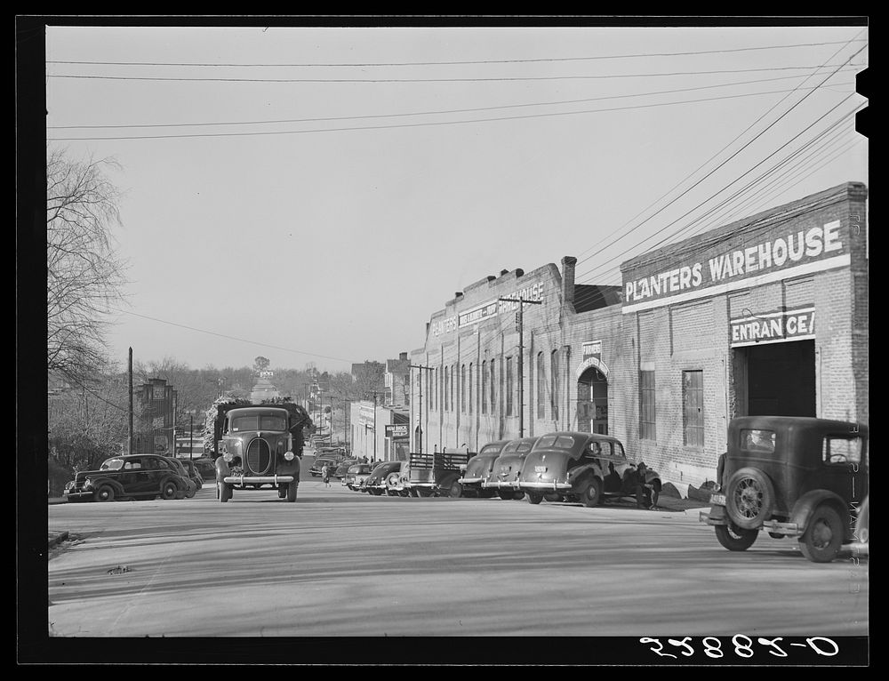 Tobacco warehouses on main street of South Boston, Halifax County, Virginia. A truck is hauling a load of tobacco after the…