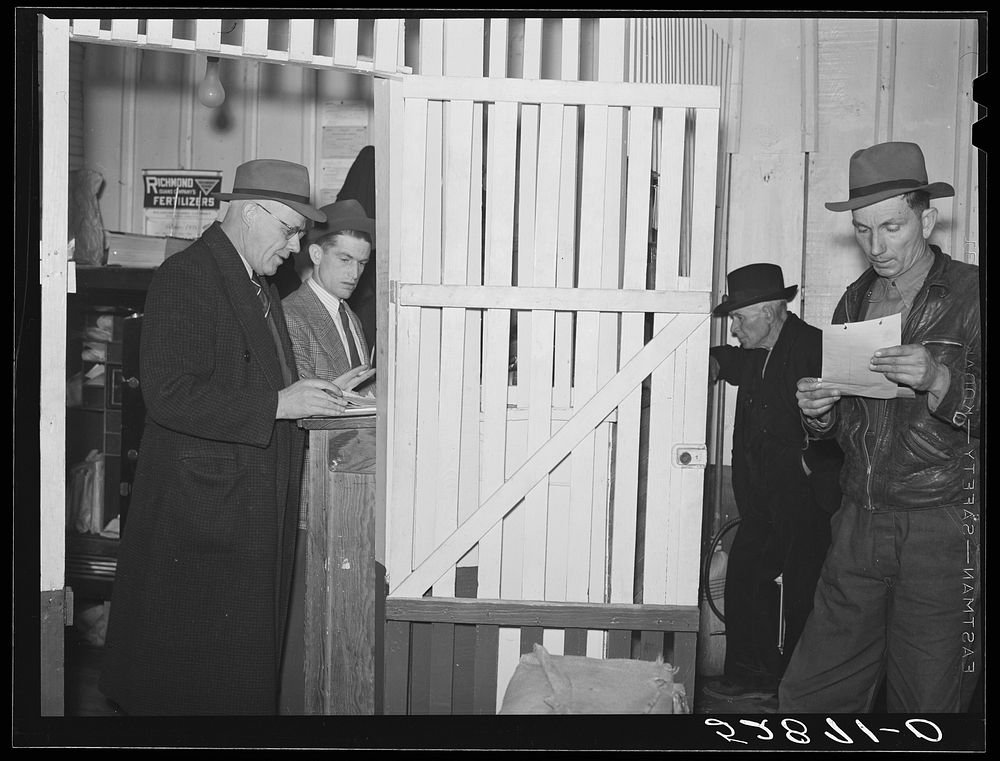 Farmers getting their checks for sale of their tobacco at auction in warehouse. Mebane, Orange County, North Carolina.…