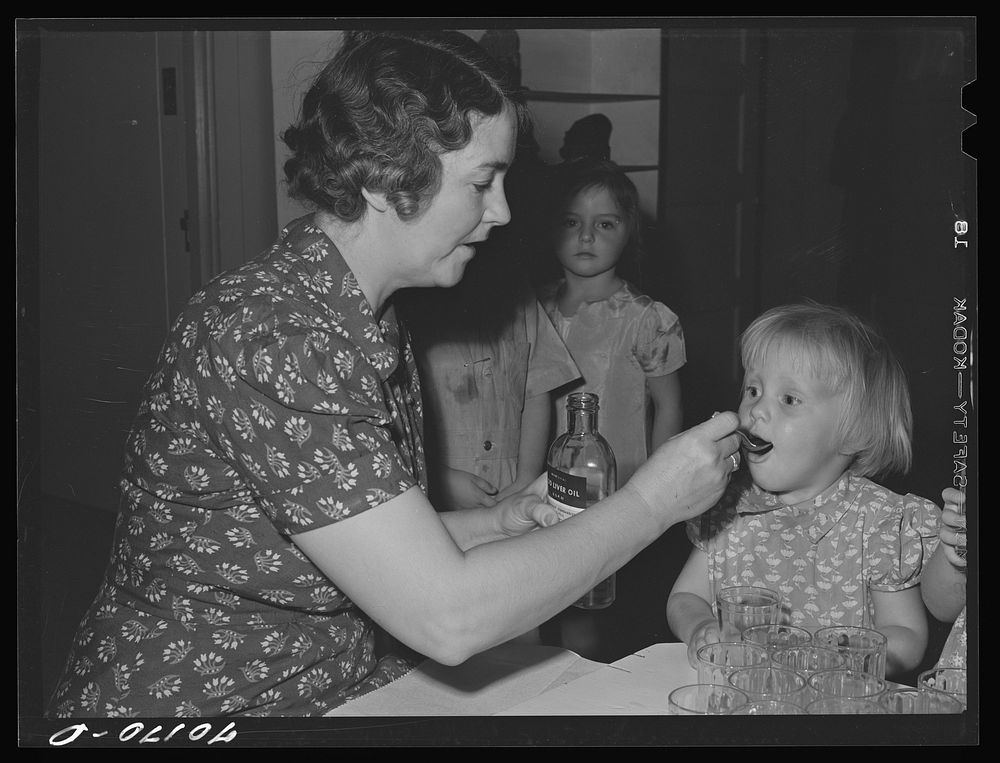 Little girl gets her morning cod liver oil at the nursery school at the FSA (Farm Security Administration) farm family…