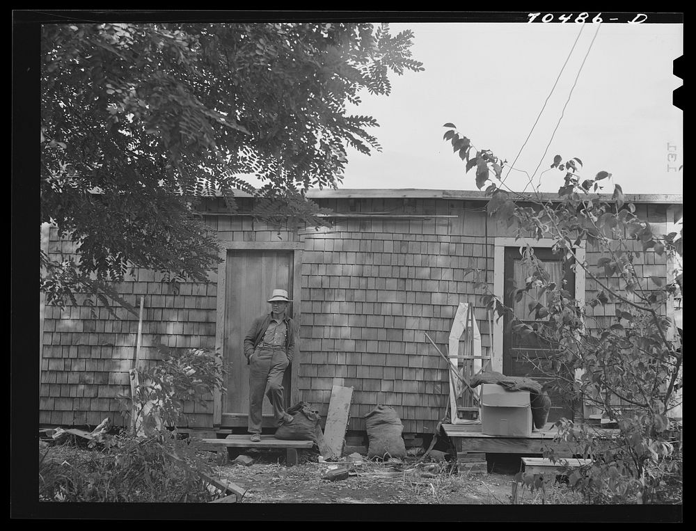 Workman at Umatilla ordnance depot, in front of house which is a converted woodshed and which he shares with another…