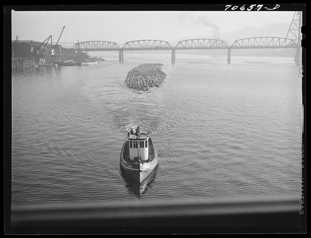 Log rafts are towed by tugs in the Willamette River. Portland, Oregon by Russell Lee