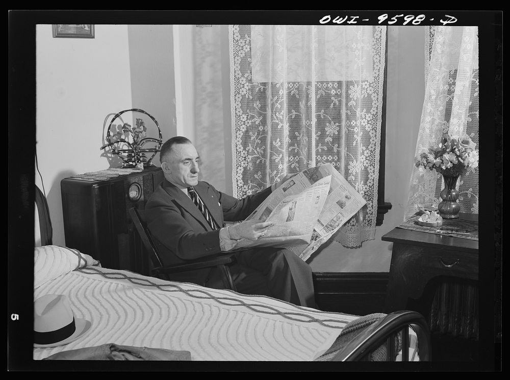 Butte, Montana. John Herlihy, a shift boss at the Mountain Con mine, reading a newspaper at home by Russell Lee