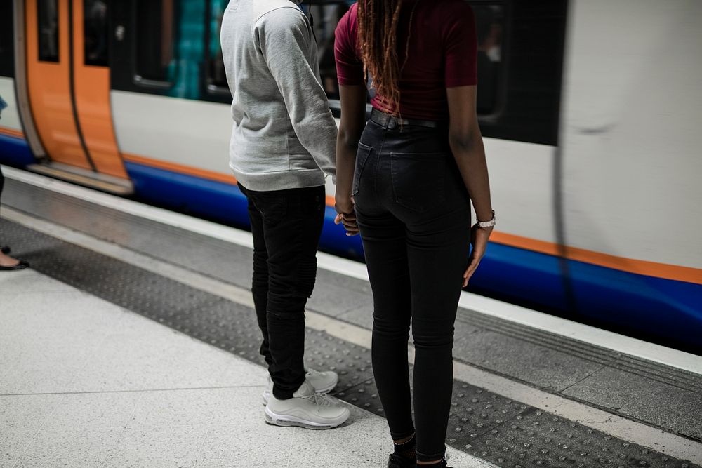 Couple holding hands as the train goes by