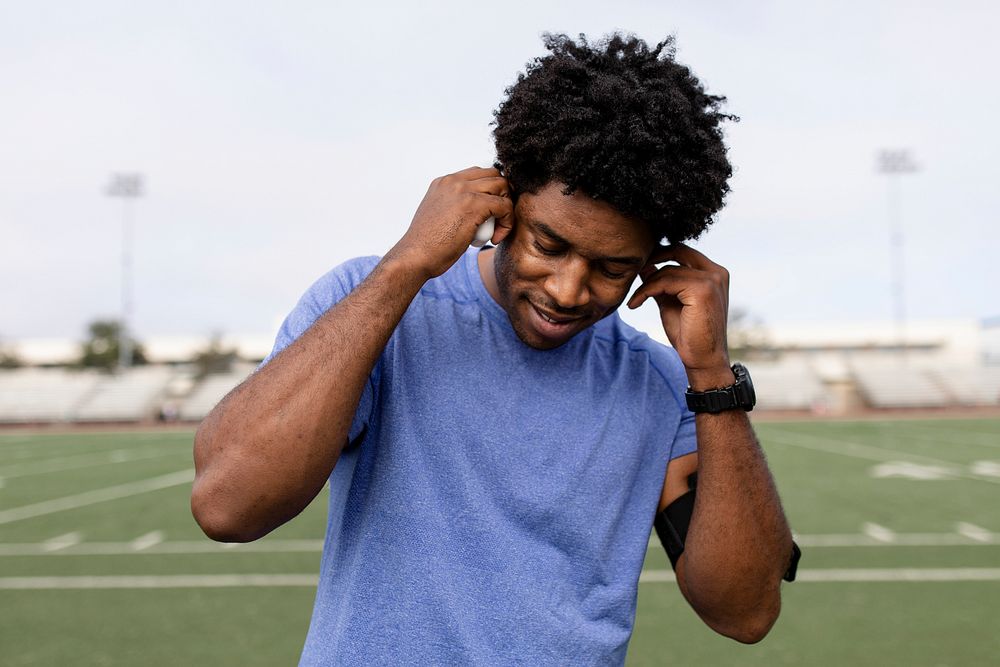 Man athlete putting the earbud on his ears and listening to the music
