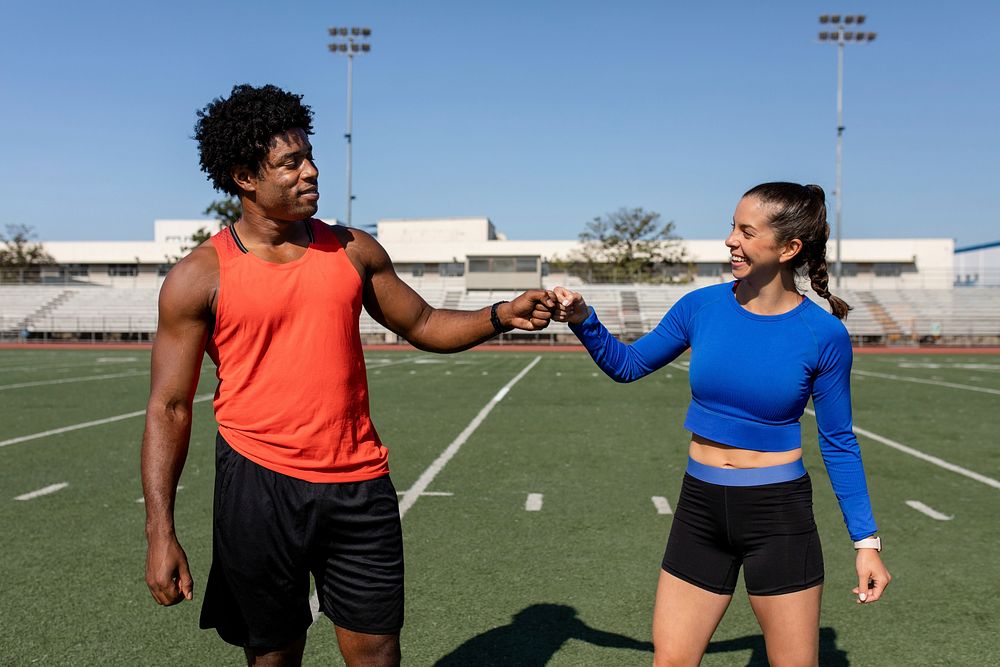 Male and female athletes fist bumping