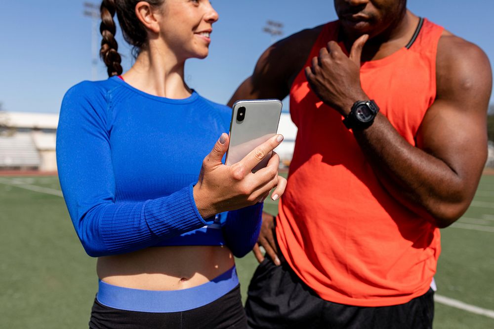 Male and female athletes looking at smartphone 
