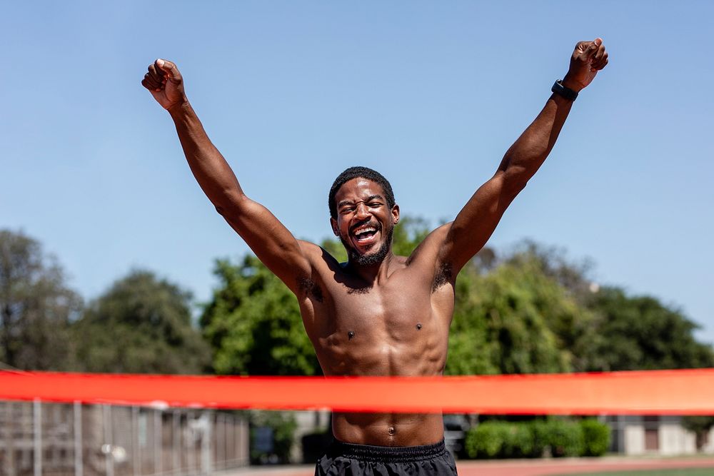 Black man runner winnning with arms open, athletic race competition