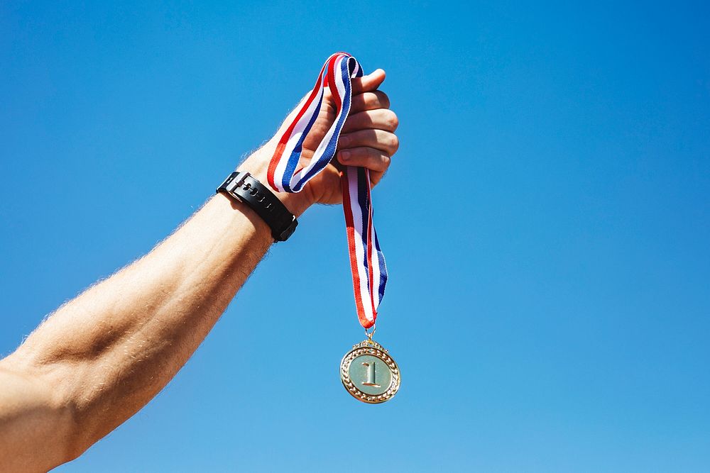 Man holding a gold medal after winning a race 