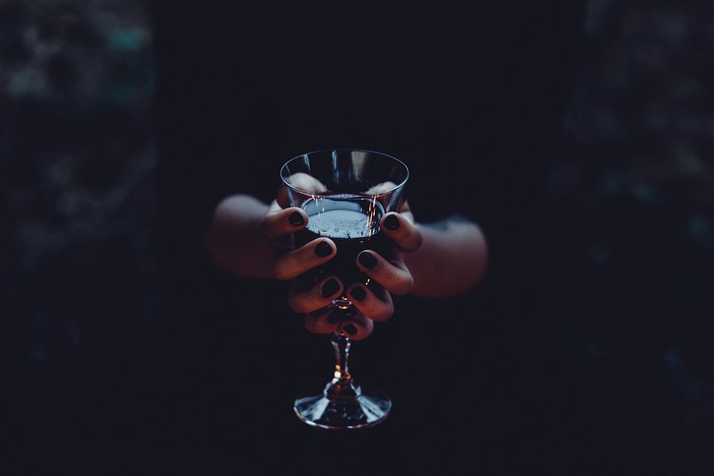 Free women holding goblet wine glass in dark bakcground photo, public domain beverage CC0 image.