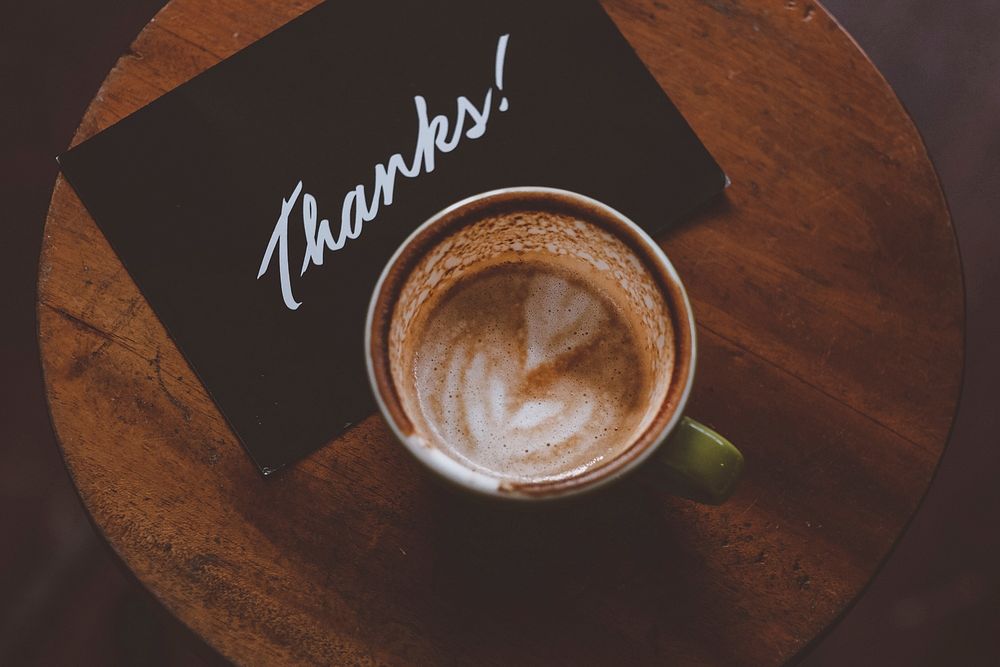 Free coffee latte art cup with thank you card on wooden table top view public domain CC0 photo.