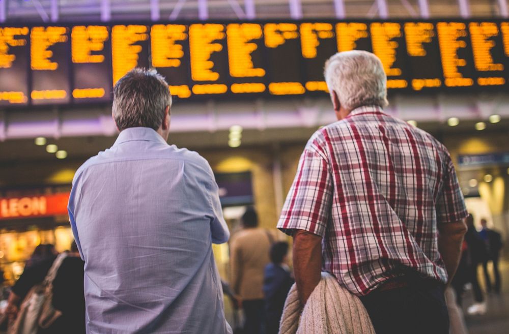 Free two men checking timetable at train station image, public domain people CC0 photo.