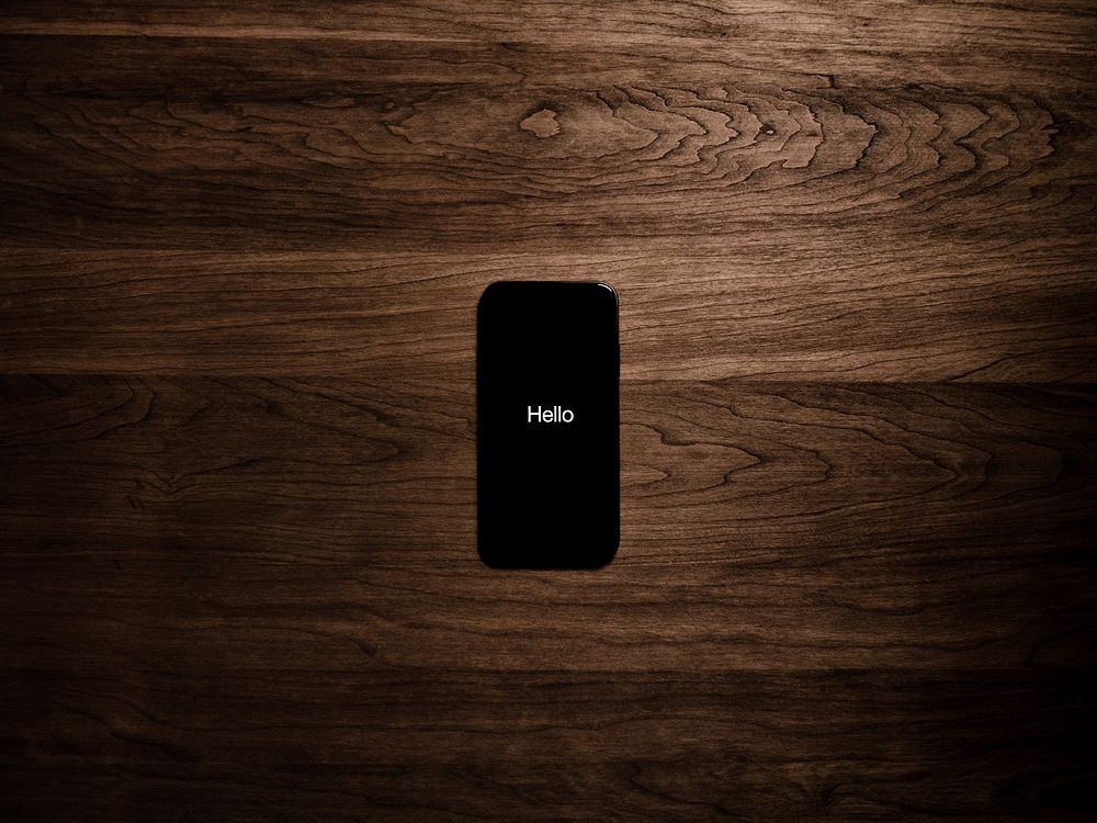 Free hello screen on iPhone on wood background image, public domain CC0 photo.