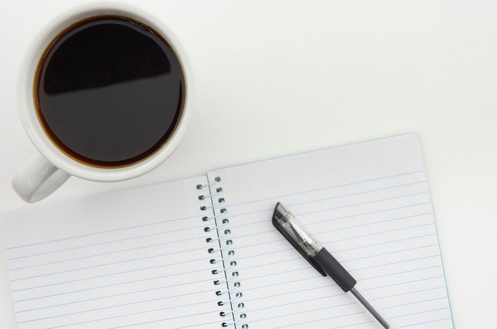 Free flat lay view of a cup of coffee and a notebook photo, public domain work CC0 image.