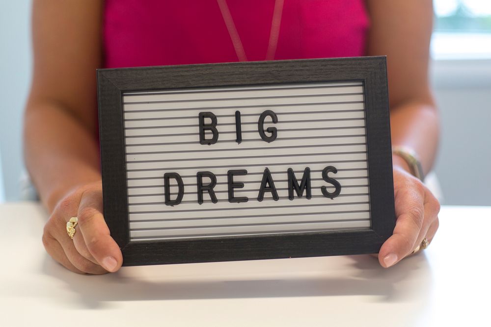 Free big dreams sign held by a woman image, public domain CC0 photo.