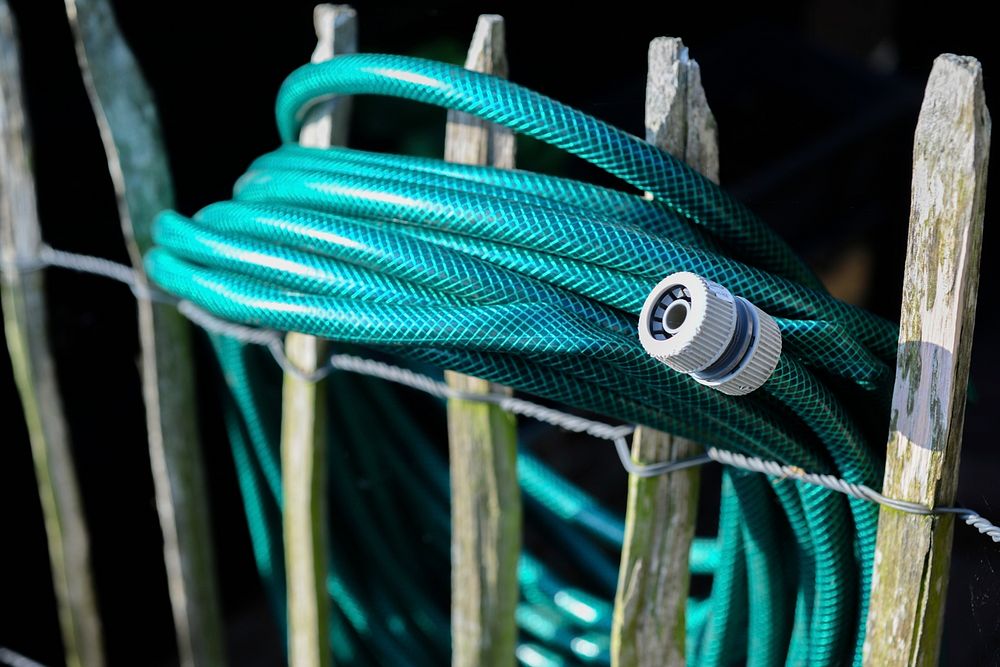 Free blue sprinkler on fence photo, public domain garden CC0 image.