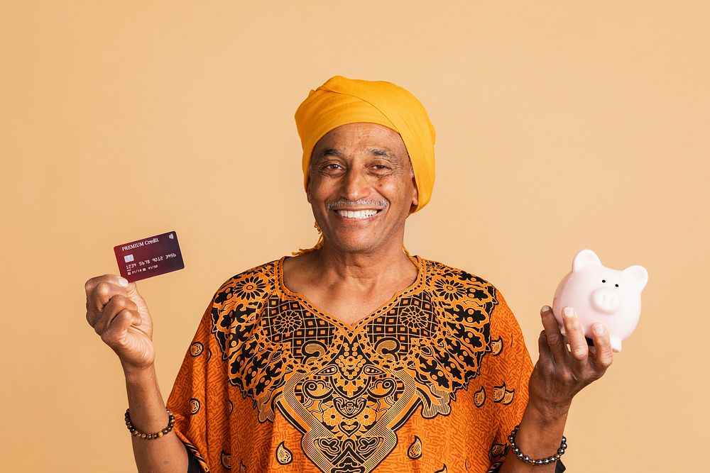 Happy mixed Indian man with a credit card and a piggy bank 