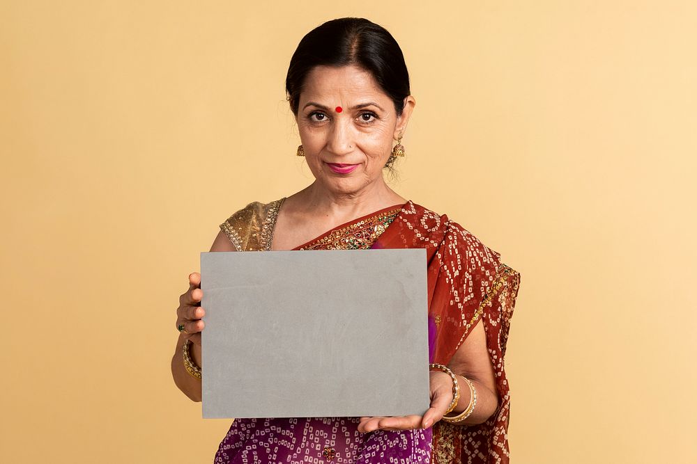 Indian woman in a traditional saree holding a paper mockup 