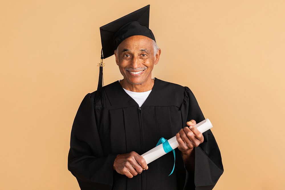 Proud senior man in a graduation gown holding his diploma