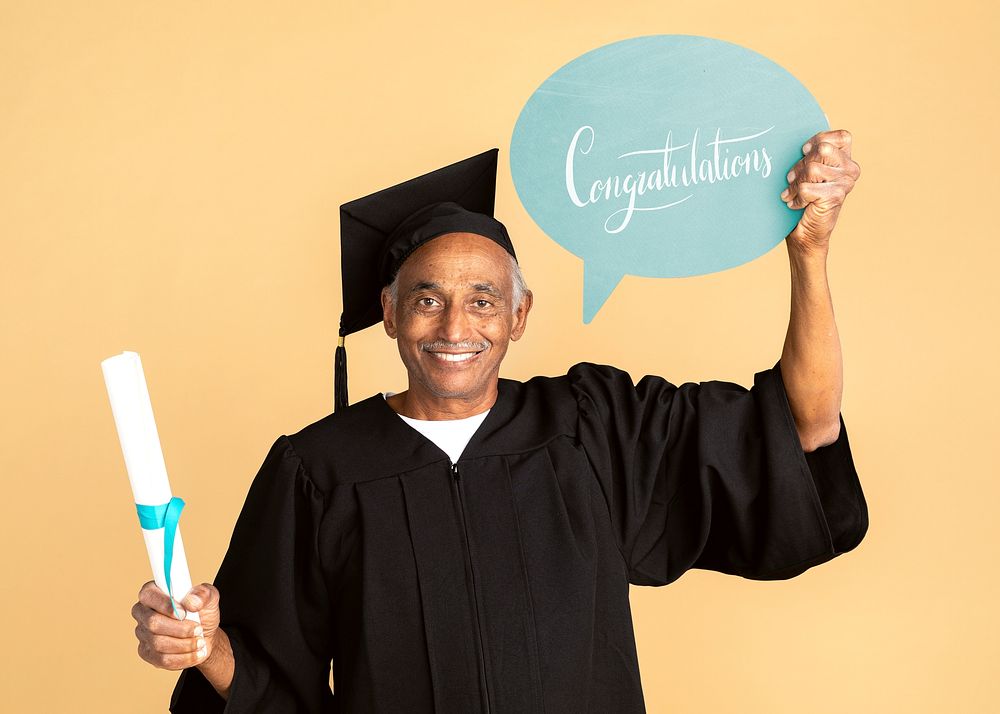 Proud senior man in a graduation gown holding a congratulations speech bubble mockup 