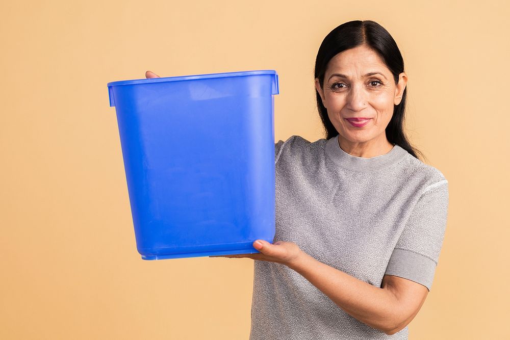 Senior Indian woman holding an empty blue container 