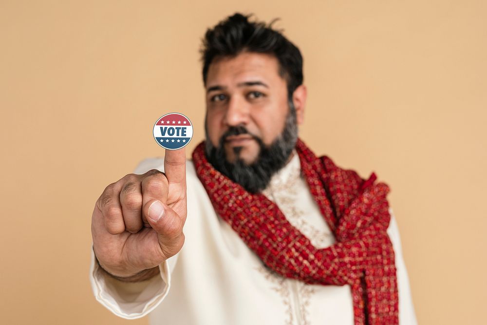 Indian man in a kurta showing a vote sticker