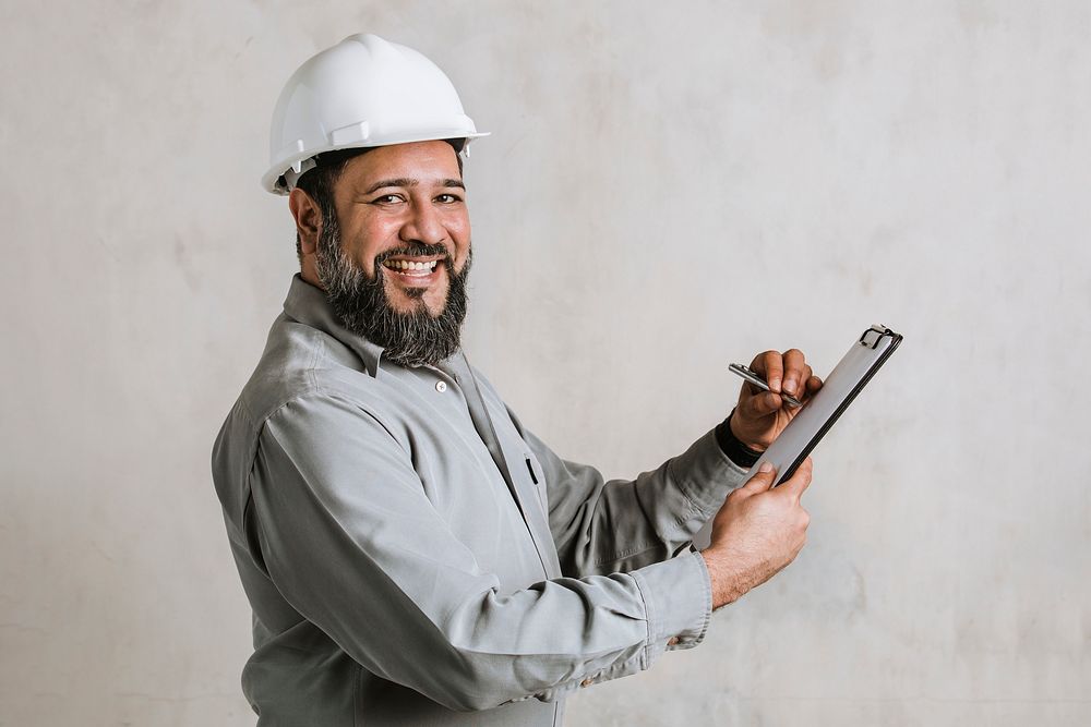 Indian engineer writing on a paper clipboard