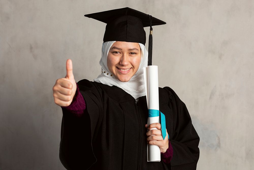 Muslim woman in a graduation gown holding her diploma 